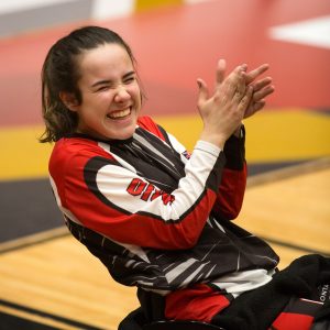 A young girl athlete smiles and claps her hands during a wheelchair basketball game